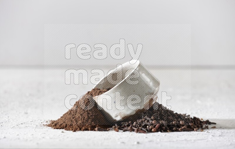 A beige ceramic bowl with cloves powder spilled out of it on a textured white flooring