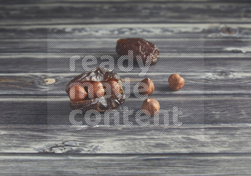 two hazelnut stuffed madjoul dates on a wooden grey background