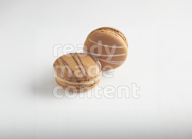 45º Shot of of two assorted Brown Irish Cream, and light brown  Almond Cream macarons on white background