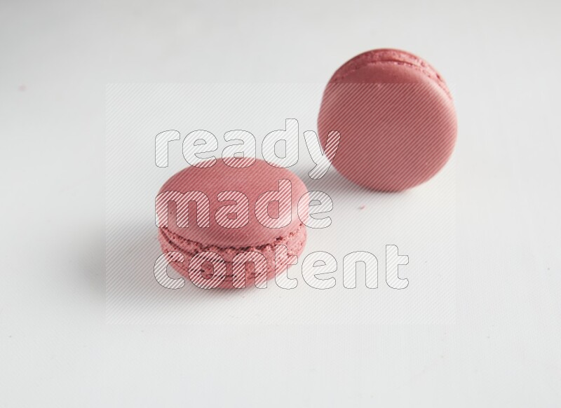 45º Shot of two Pink Raspberry macarons on white background