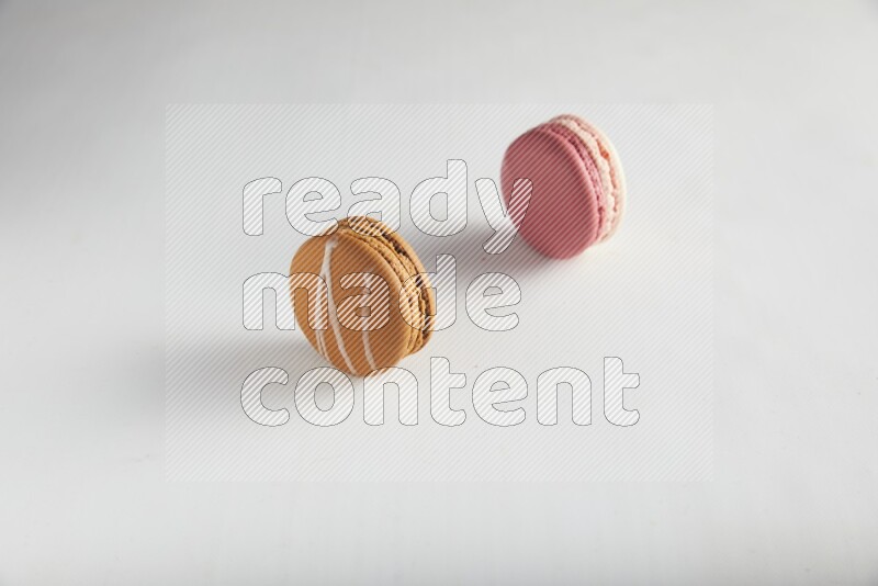 45º Shot of of two assorted Brown Irish Cream, and Pink Litchi Raspberry macarons on white background
