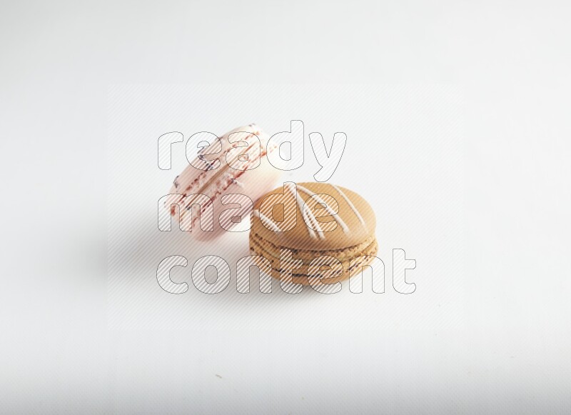 45º Shot of of two assorted Brown Irish Cream, and pink orange blossom macarons on white background