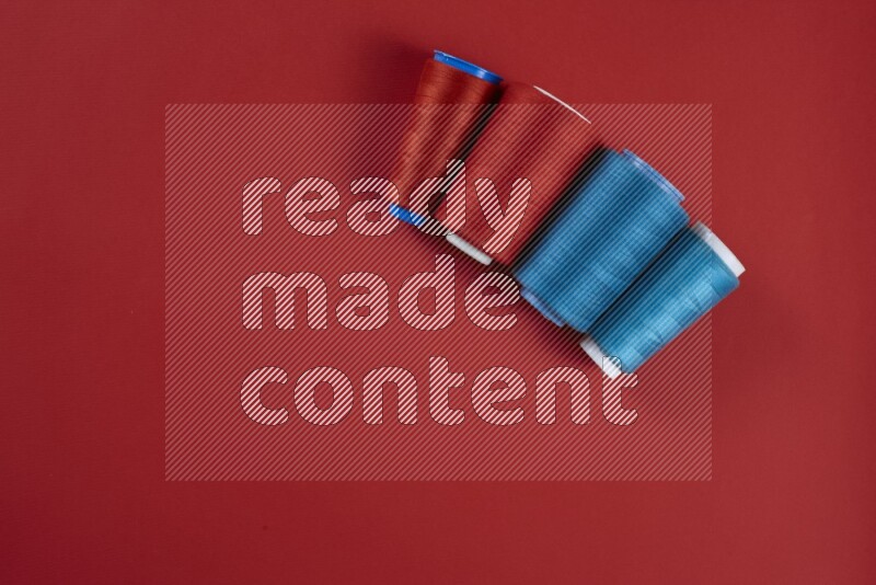 مجموعة من أدوات الخياطة والتفصيل زرقاء وحمراء اللون على خلفية حمراء