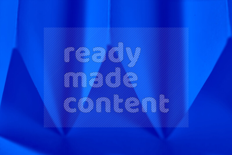 A close-up abstract image showing sharp geometric paper folds in blue gradients