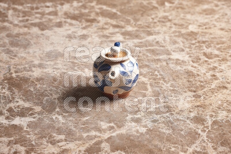 A pottery teapot on beige marble background