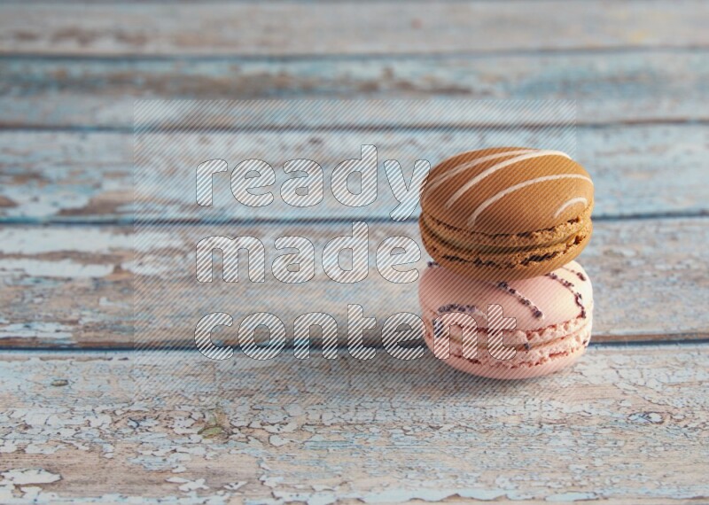 45º Shot of of two assorted Brown Irish Cream, and pink orange blossom  macarons on light blue background