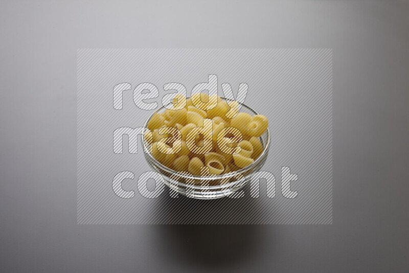 Pipe pasta in a glass bowl on grey background