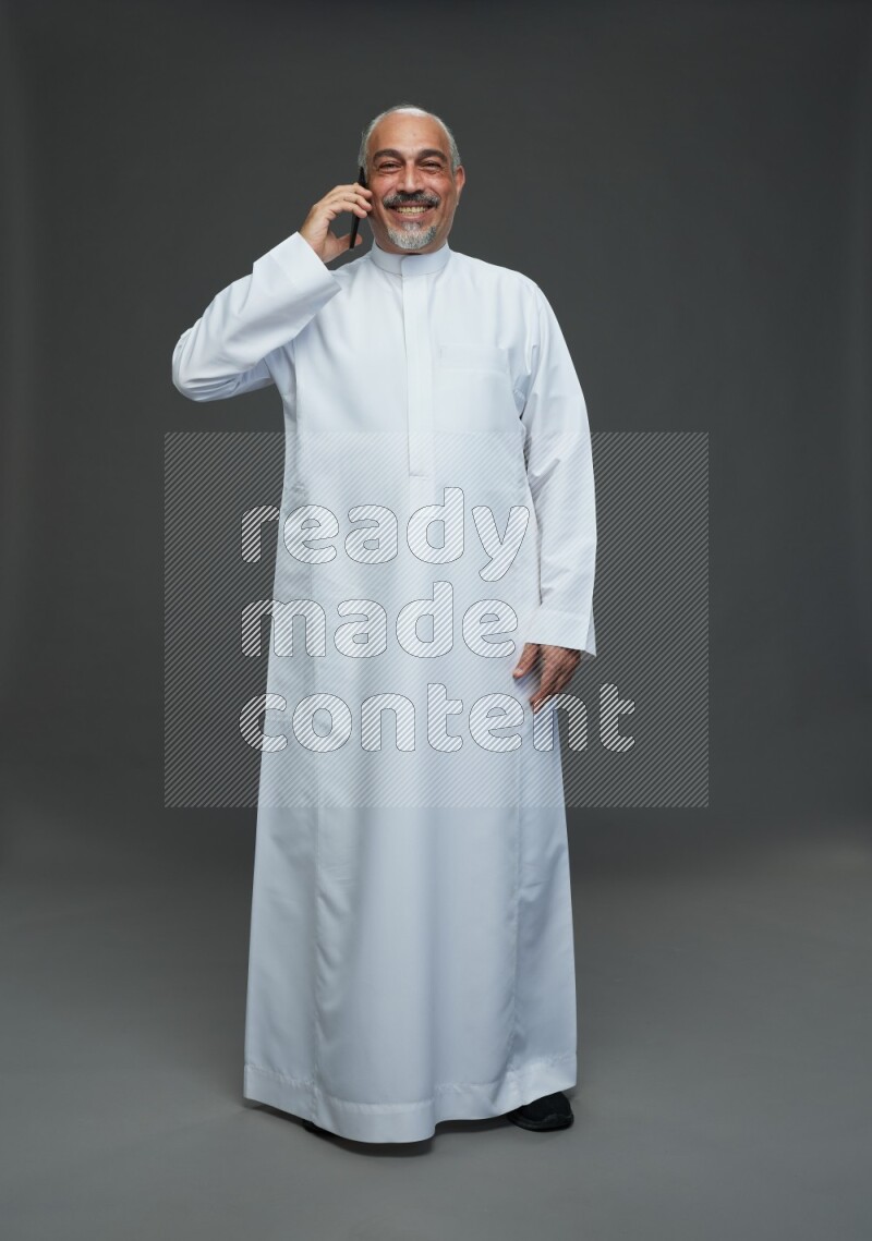 Saudi man without shomag Standing talking on phone on gray background