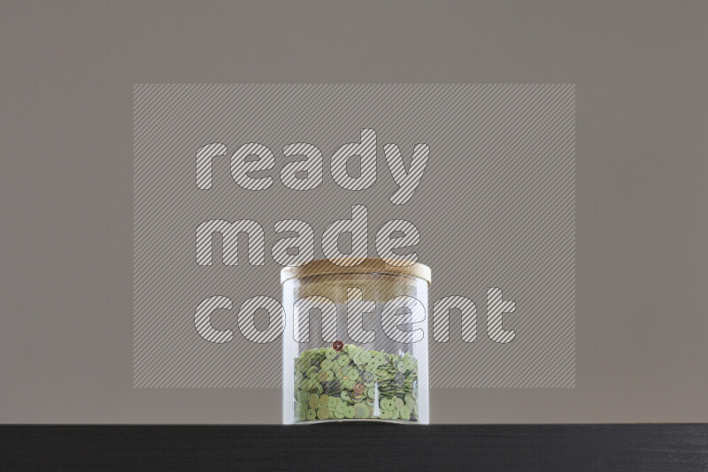 Sequins in a glass jar on black background
