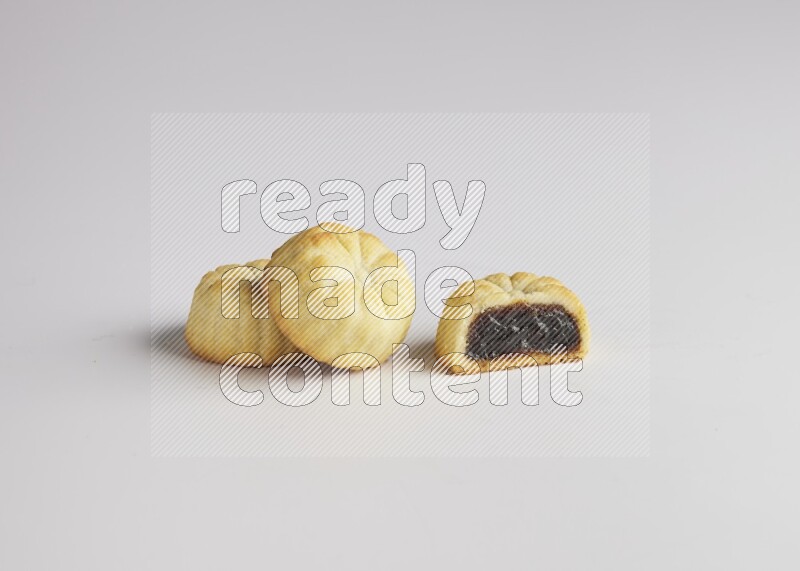Three Pieces of Maamoul filled with date one of them is cut direct on white background