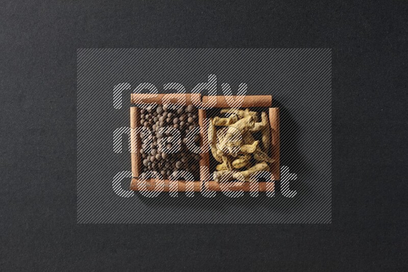 2 squares of cinnamon sticks full of allspice and turmeric fingers on black flooring