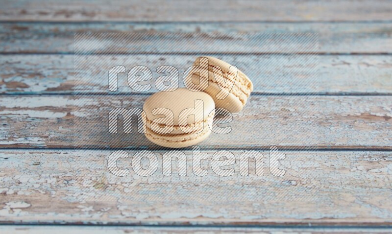 45º Shot of two White Caramel fleur de sel macarons on a light blue wooden background