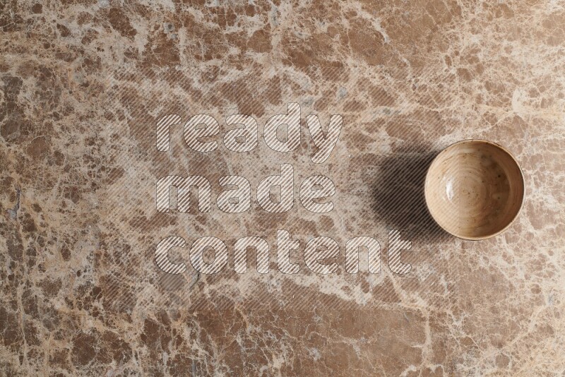 A beige pottery bowl on beige marble background