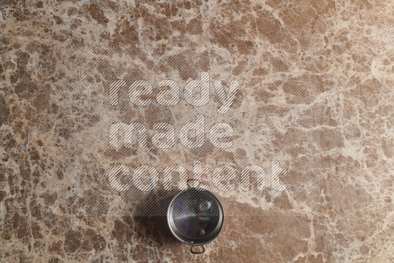 A small copper pot on beige marble background