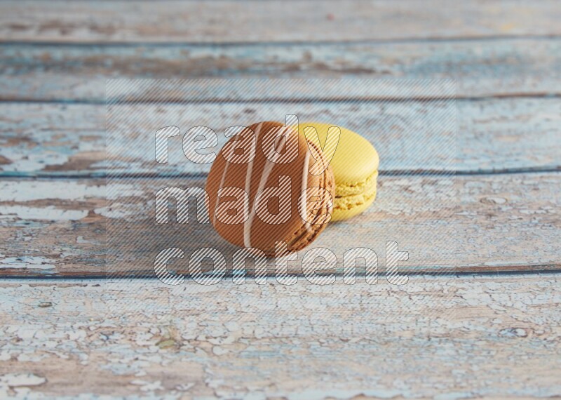 45º Shot of of two assorted Brown Irish Cream, and Yellow Lemon macarons on light blue background