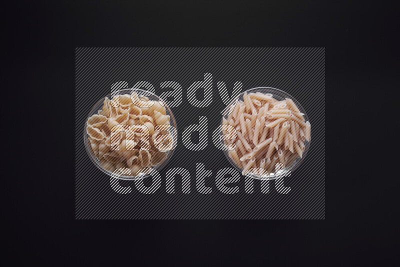 Different pasta types in glass bowls on black background