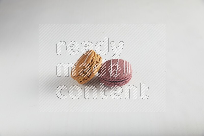 45º Shot of of two assorted Brown Irish Cream, and Red Poppy Flower macarons on white background