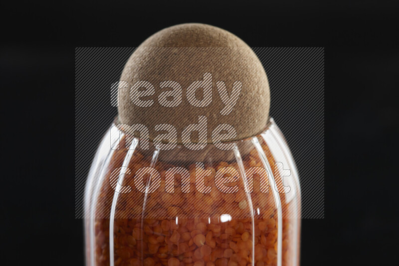 Lentils in a glass jar on black background