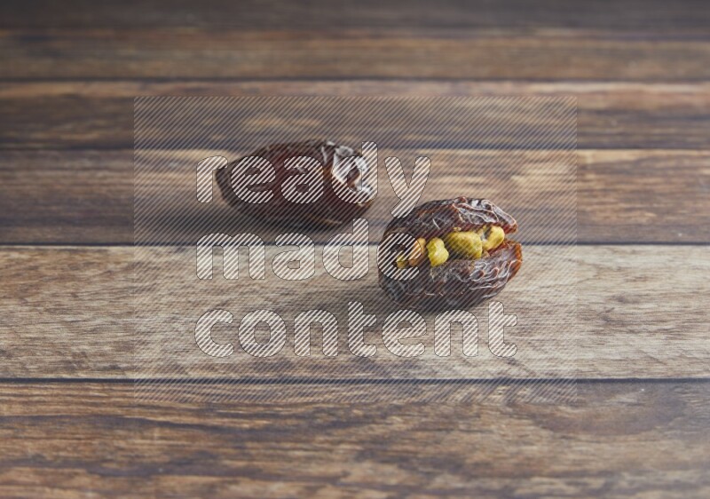 two pistachio stuffed madjoul date on a wooden background