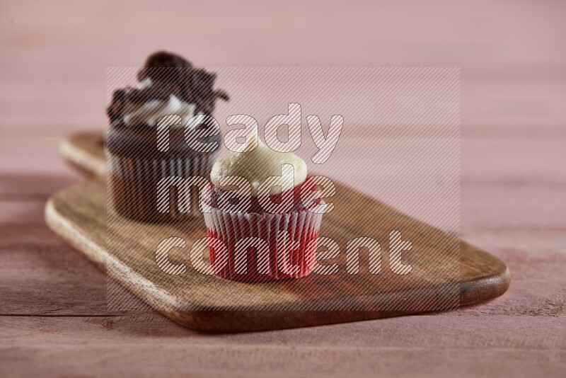 Red velvet mini cupcake topped with cream on a wooden board
