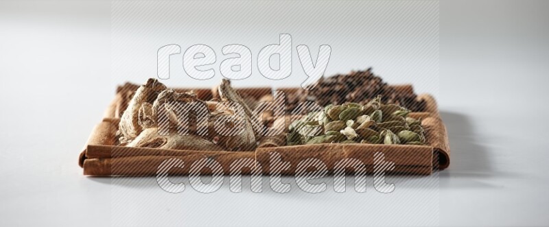 4 squares of cinnamon sticks full of cardamom, cinnamon, cloves and dried ginger on white flooring