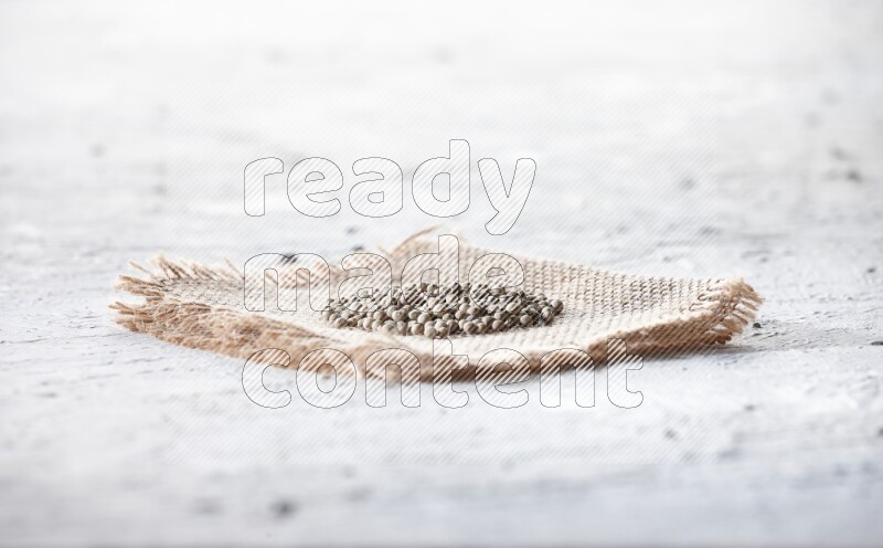 White pepper beads on a burlap piece of fabric on textured white flooring