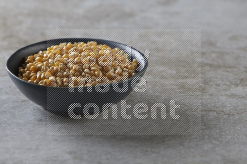 corn kernel in a black ceramic bowl on a grey textured countertop