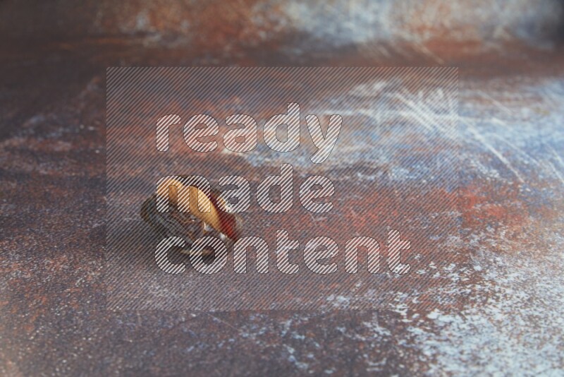 one almond stuffed madjoul date on a rustic reddish background