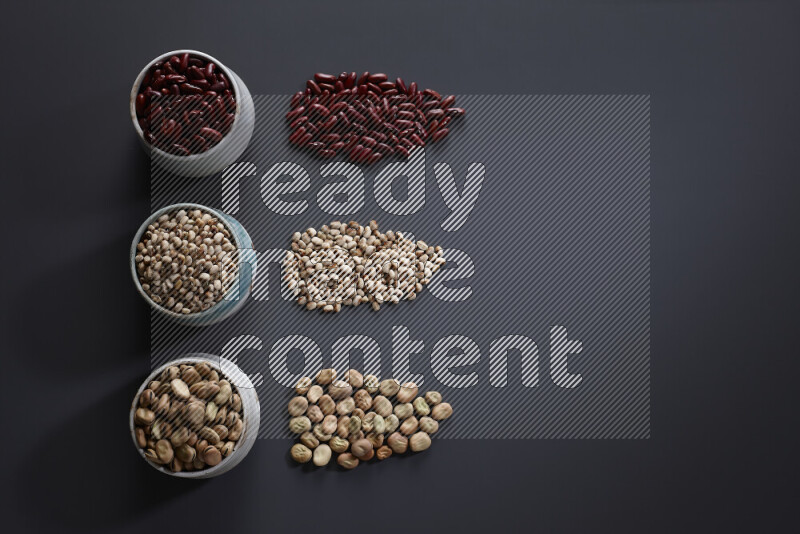 Legumes in pottery bowls on grey background