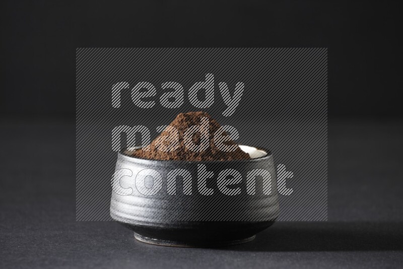 وعاء فخاري أسود ممتلئ ببودرة القرنفل علي خلفية سوداء