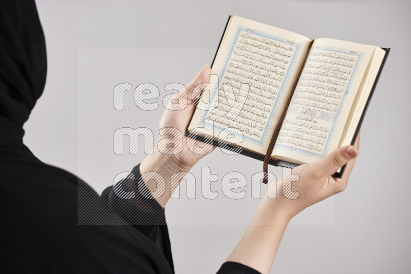 امرأة تحمل بيديها مصحف القرآن في أوضاع متعددة