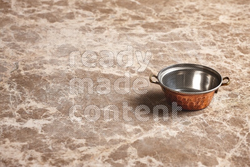A small copper pot on beige marble background