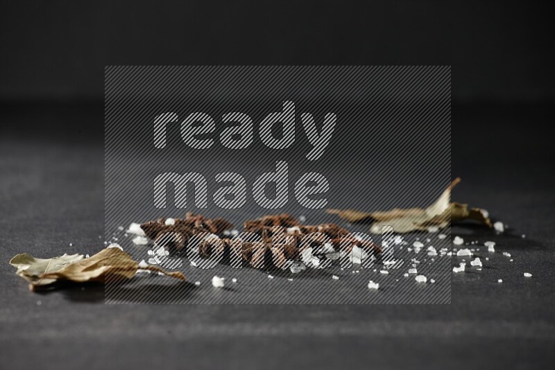 Salt, star anise and bay laurel on black flooring