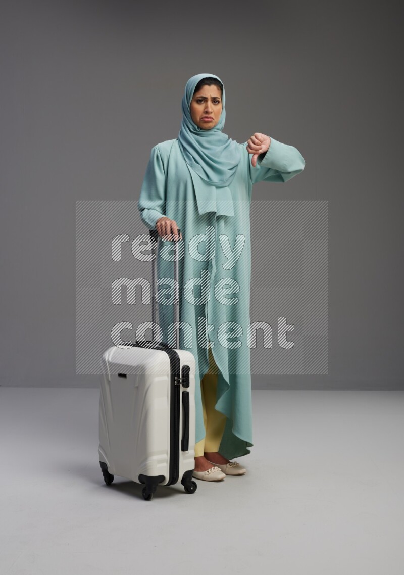 Saudi Woman wearing Abaya standing holding Travel bag on Gray background
