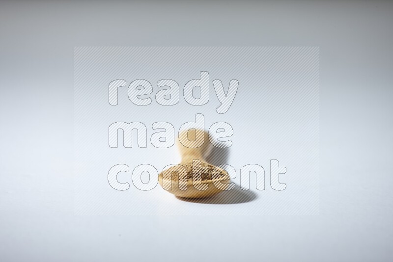 ملعقة خشبية ممتلئة ببودرة الكمون على خلفية بيضاء