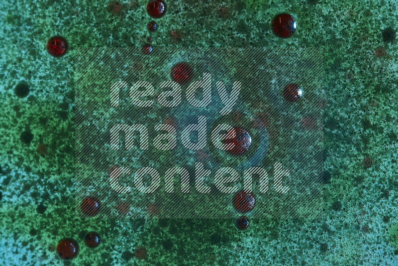 لقطات مقربة لقطرات ألوان مائية حمراء وخضراء على سطح الزيت على خلفية خضراء