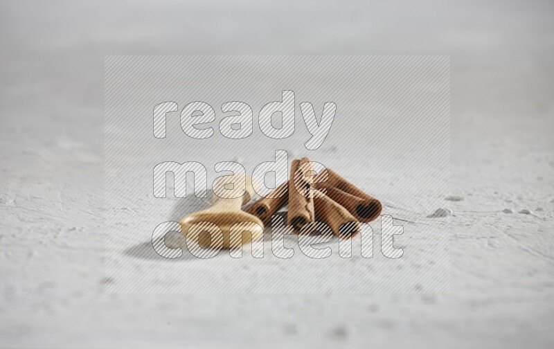 Cinnamon powder in a wooden spoon with cinnamon sticks on white background