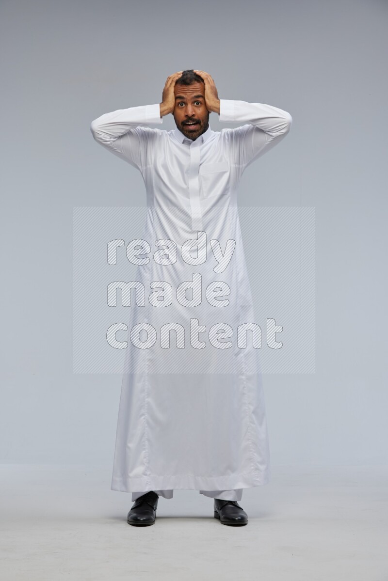 Saudi man Wearing Thob standing interacting with the camera on Gray background