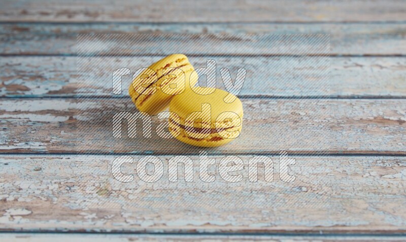45º Shot of two Yellow Lemon macarons on light blue wooden background