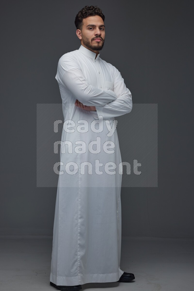 A Saudi man wearing Thobe standing and making different poses eye level on a gray background