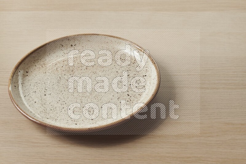 A beige pottery plate on light wooden background