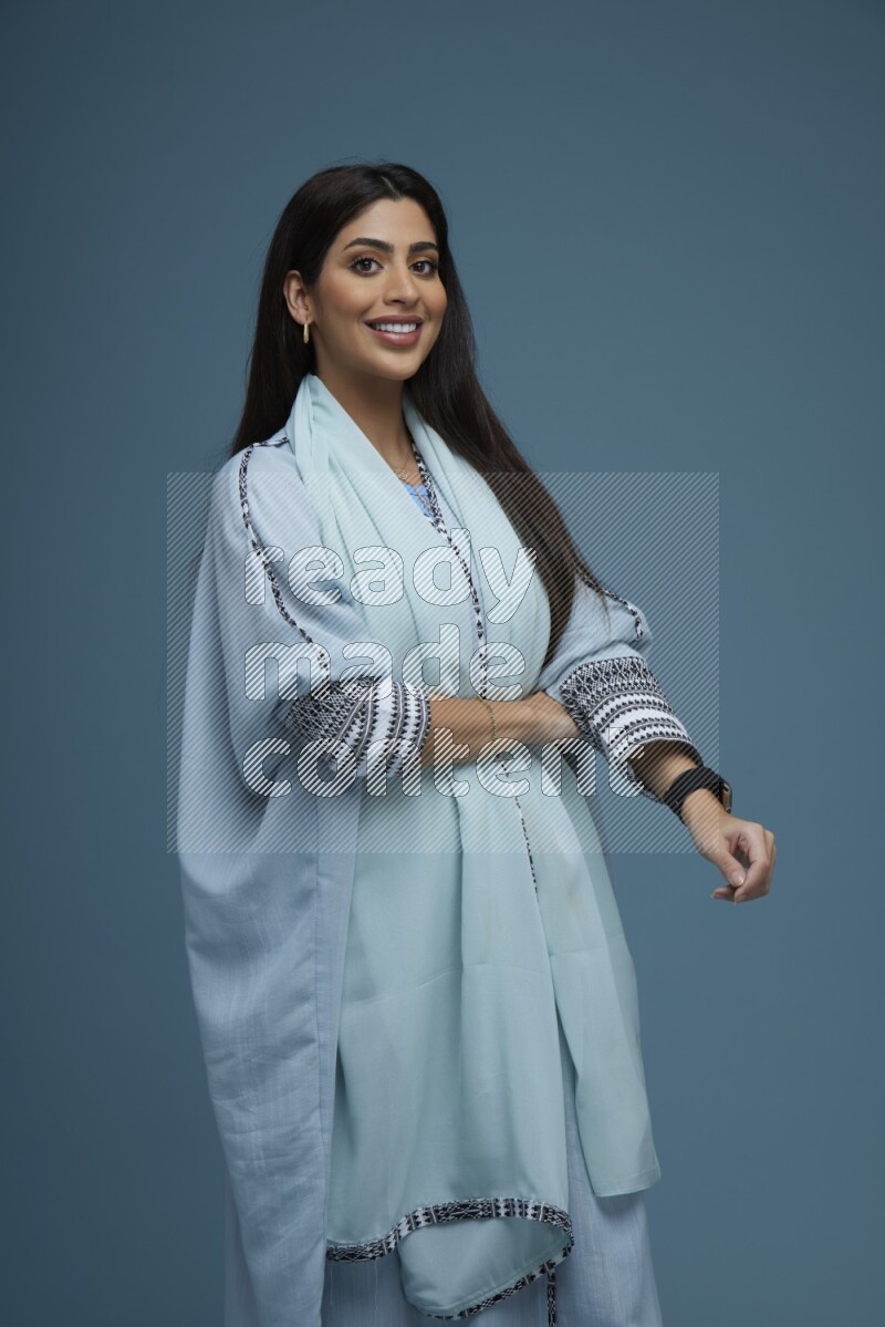 A woman posing in a blue background wearing blue Abaya no Hijab