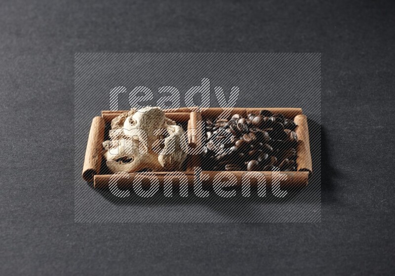 مربعان من أعواد القرفة ممتلئان بحبوب القهوة والزنجبيل المجفف علي خلفية سوداء