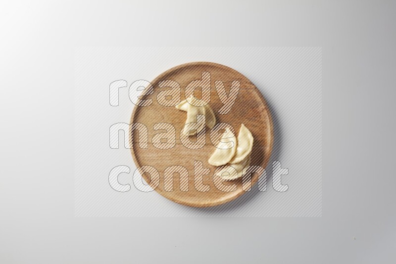 Five Sambosas on a wooden round plate on a white background