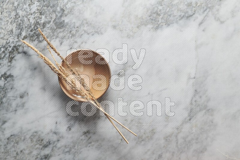 Wheat stalks on multicolored pottery plate on grey marble background