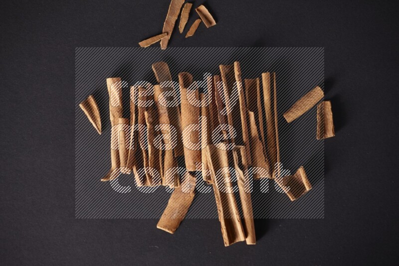 Cracked cinnamon sticks on a black background