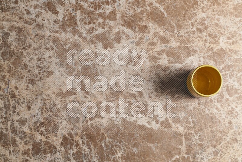 A multicolored pottery cup on beige marble background