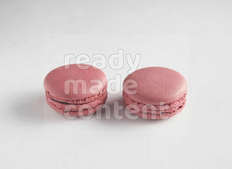 45º Shot of two Pink Raspberry macarons on white background