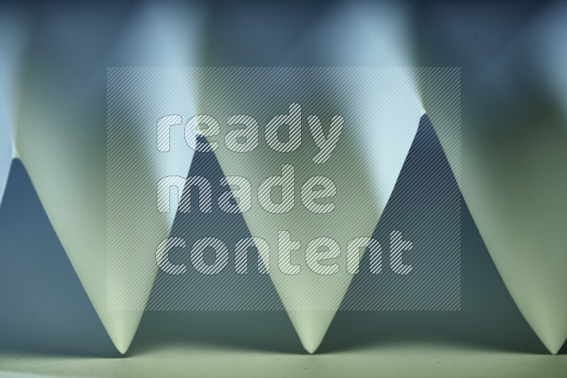 A close-up abstract image showing sharp geometric paper folds in green and blue gradients