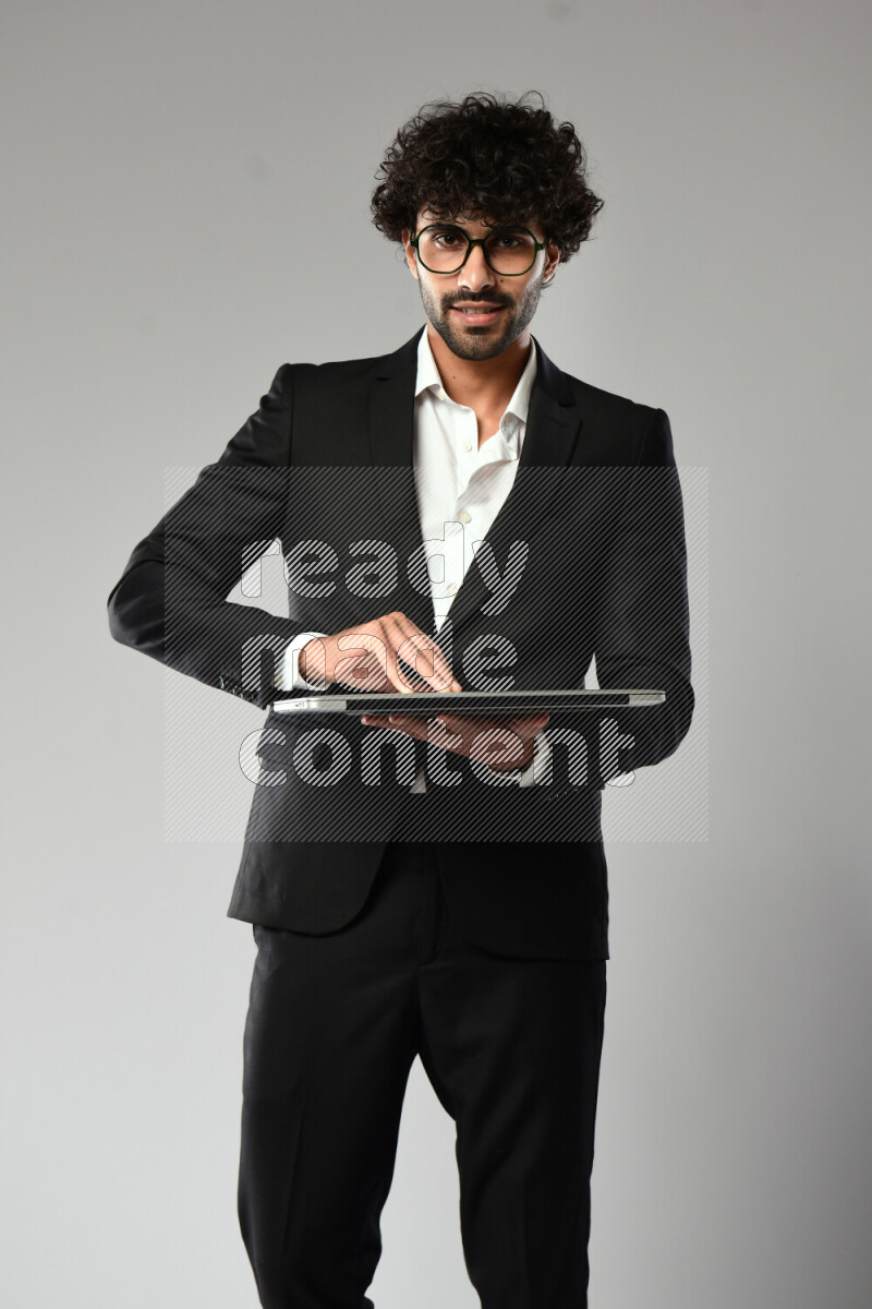 A man wearing formal standing and holding a laptop on white background